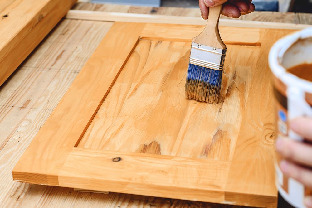 A person is painting a wooden door with a brush.