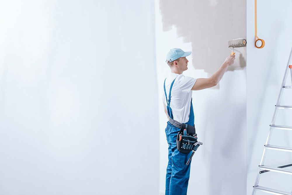 A man is painting a wall with a roller.
