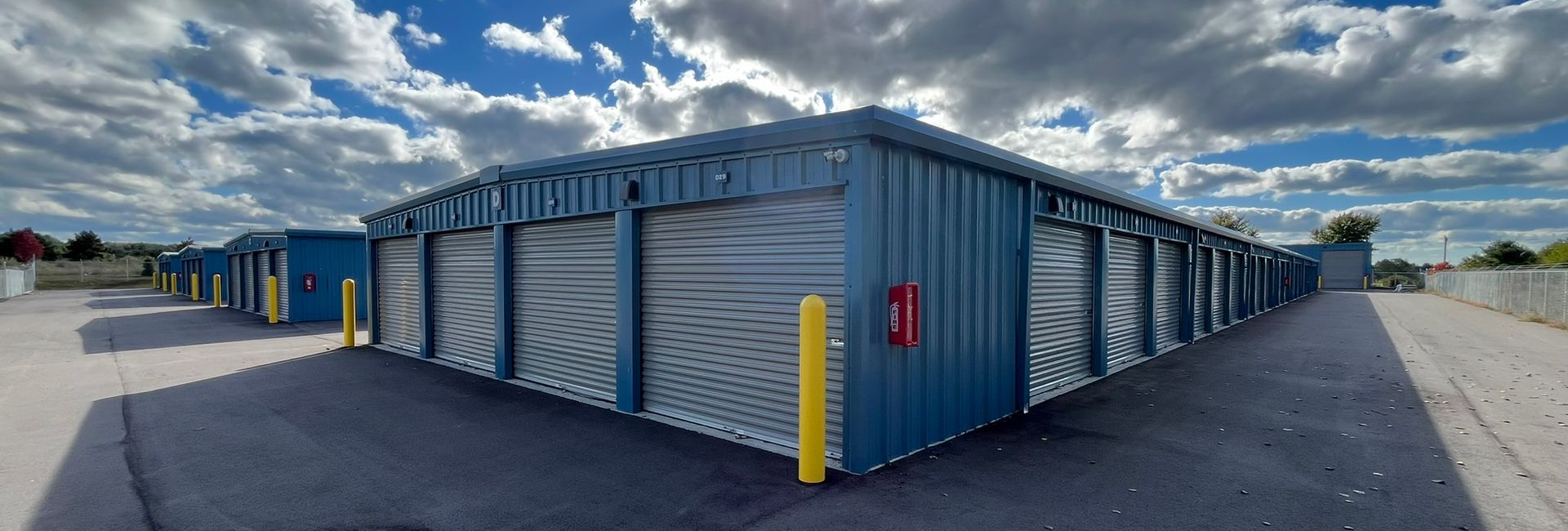 Secure drive-up storage units in Traverse City, MI at Gorilla Storage Acme, featuring roll-up doors, gated access, and spacious paved lanes under a partly cloudy sky.