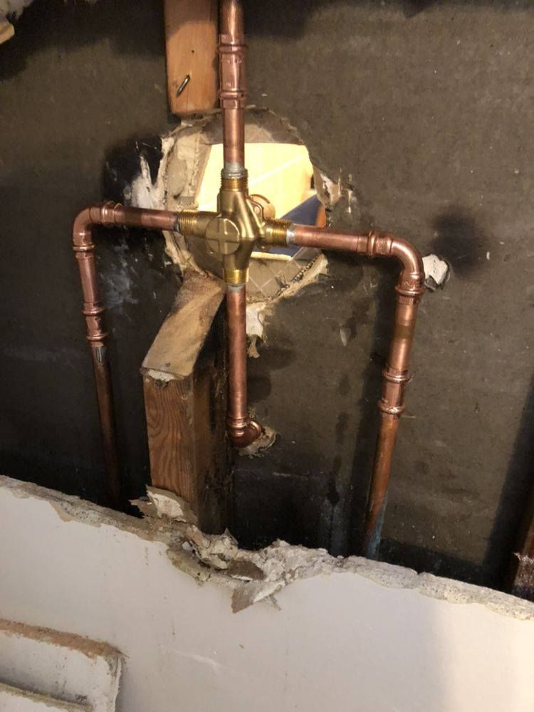 Copper plumbing rough-in with a mixing valve installed inside a wall cavity.