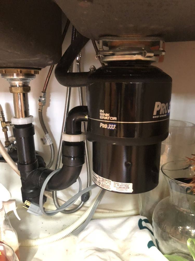 Under-sink view: a black garbage disposal (Pro Series) with plumbing connected to two sinks.