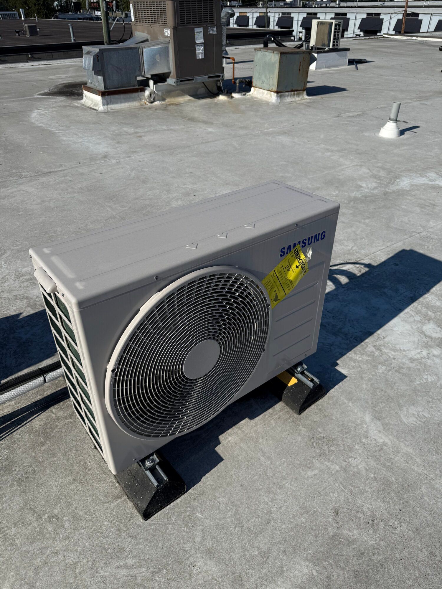 Air conditioning unit on a rooftop, gray and black, sunny day.