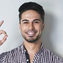 A man in a plaid shirt is smiling and giving an ok sign