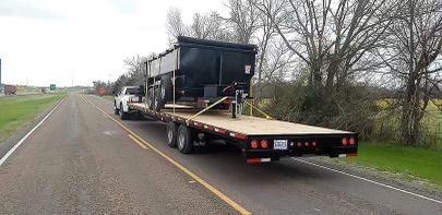 A semi truck is driving down a road with a trailer attached to it.