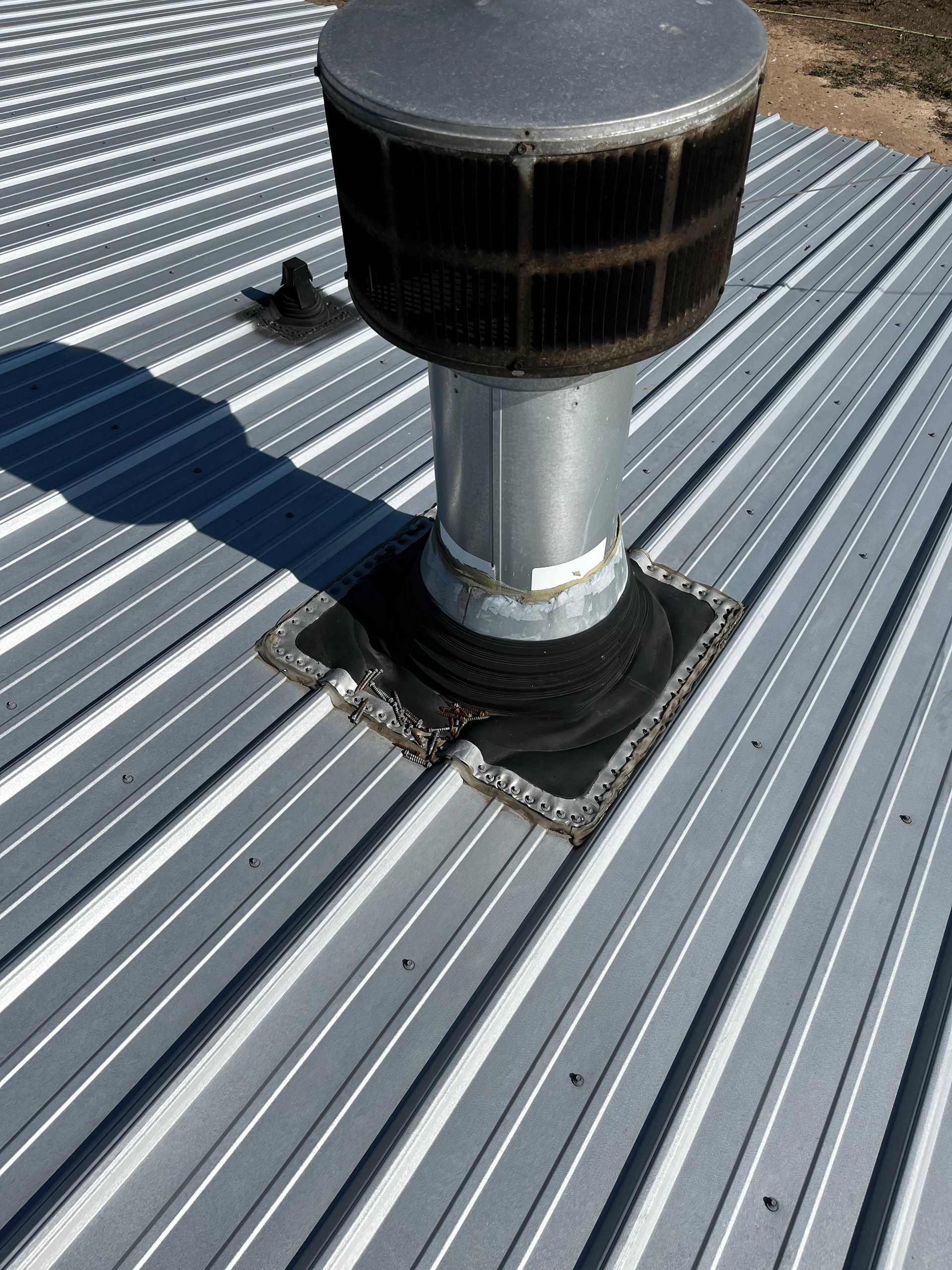 Metal roof with a vent pipe and weather protection.
