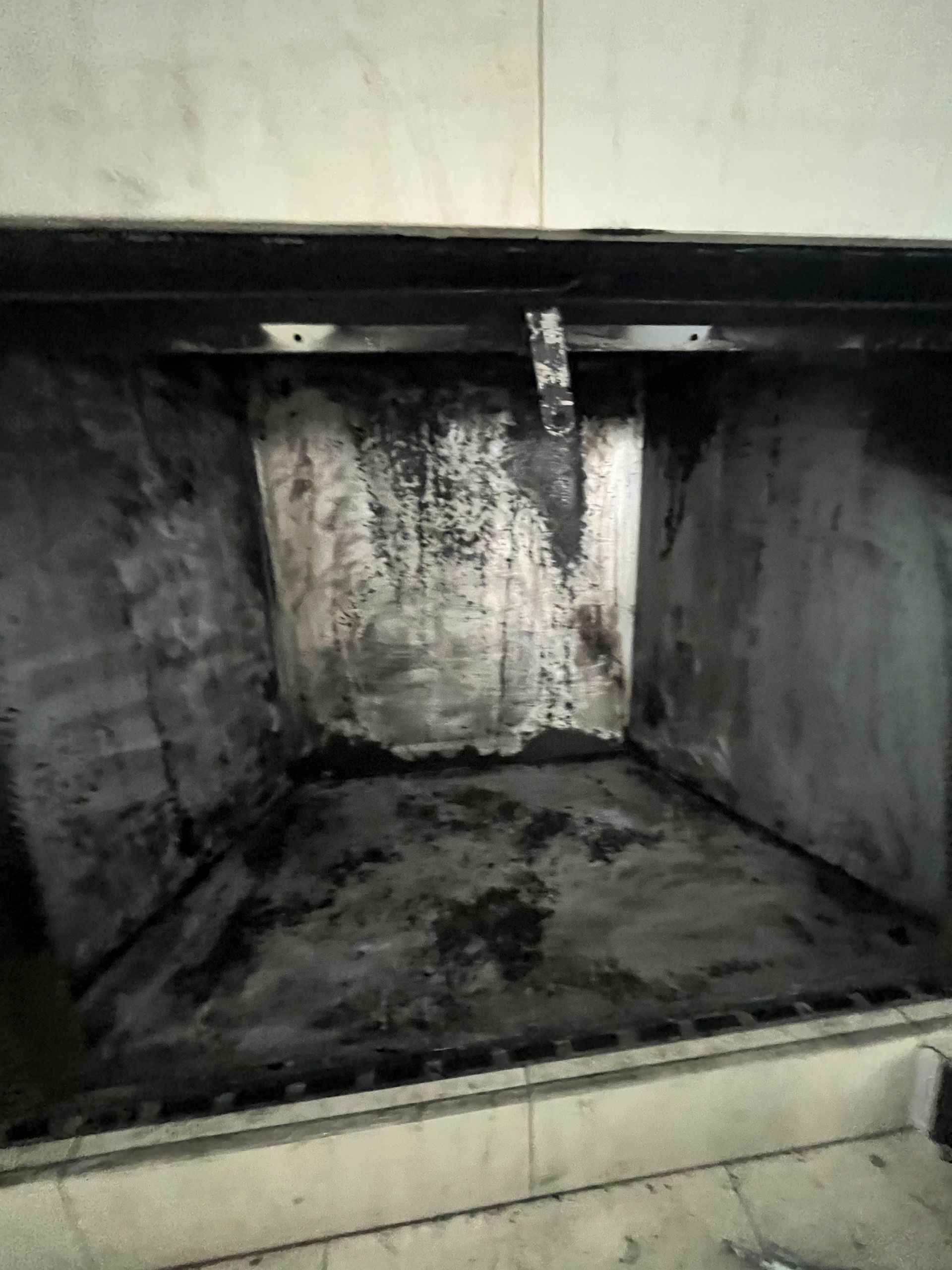 A dirty, metal vent hood interior covered in soot.
