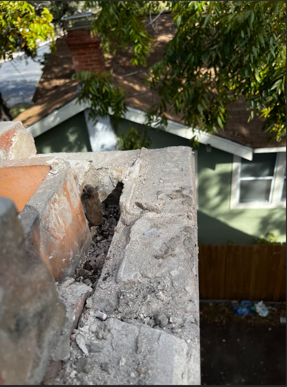 Electrician in blue uniform and mask uses a multimeter on an electrical box outside a building.