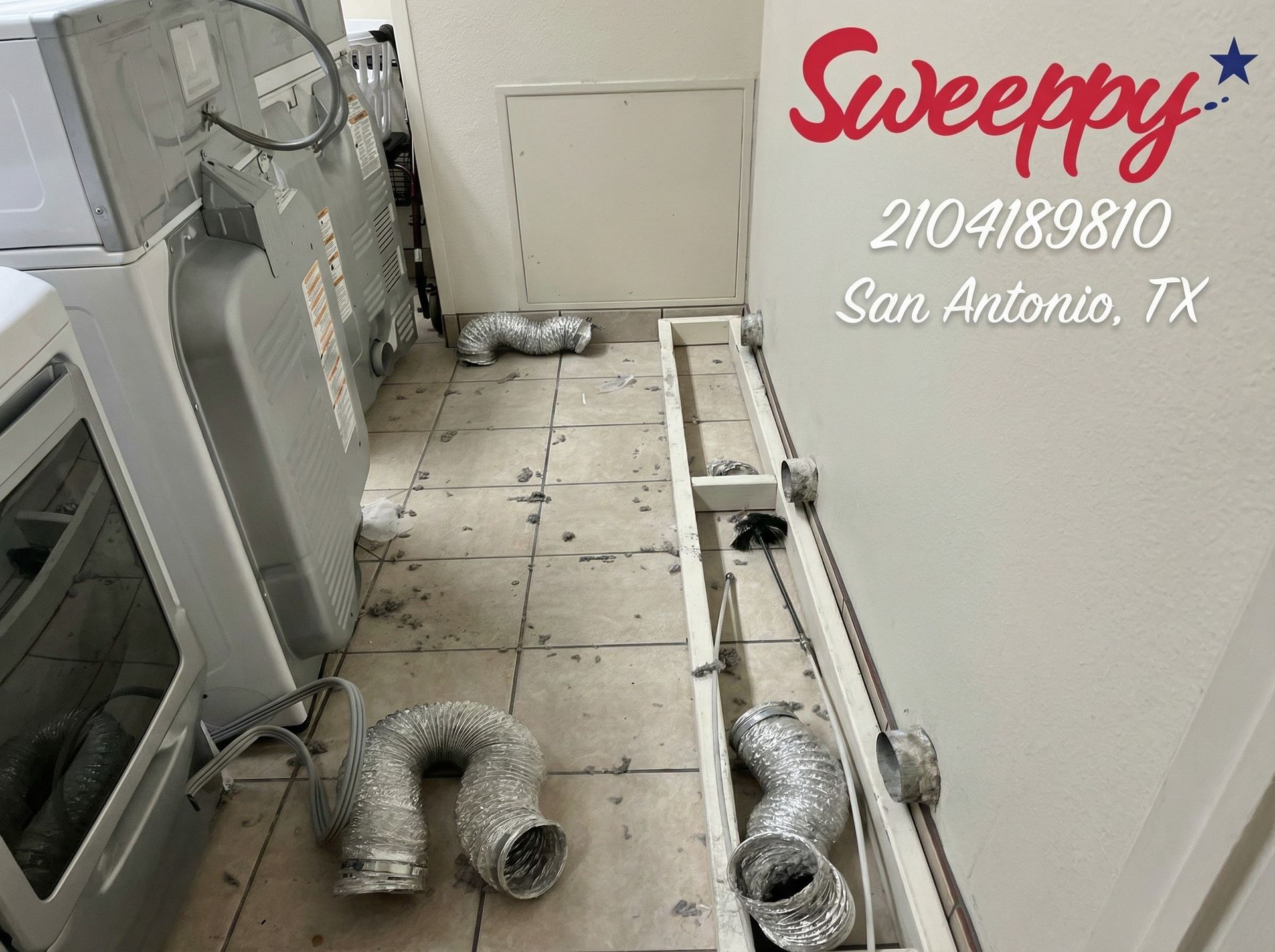 Man in blue uniform with vacuum attachment in laundry room.