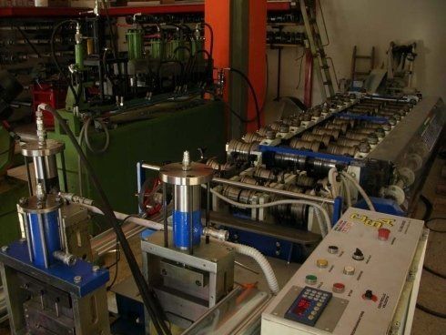 Macchinari industriali, probabilmente per la formatura dei metalli. Include pannelli di controllo, cilindri e componenti meccanici complessi.