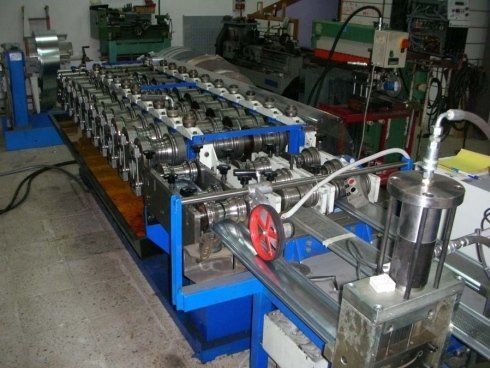 Una macchina per la formatura del metallo blu in un'officina, che modella il metallo in una forma a canale.