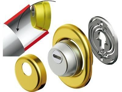 Vista esplosa di un gruppo serratura per porta con componenti color ottone, tra cui un cilindro e una piastra di protezione.