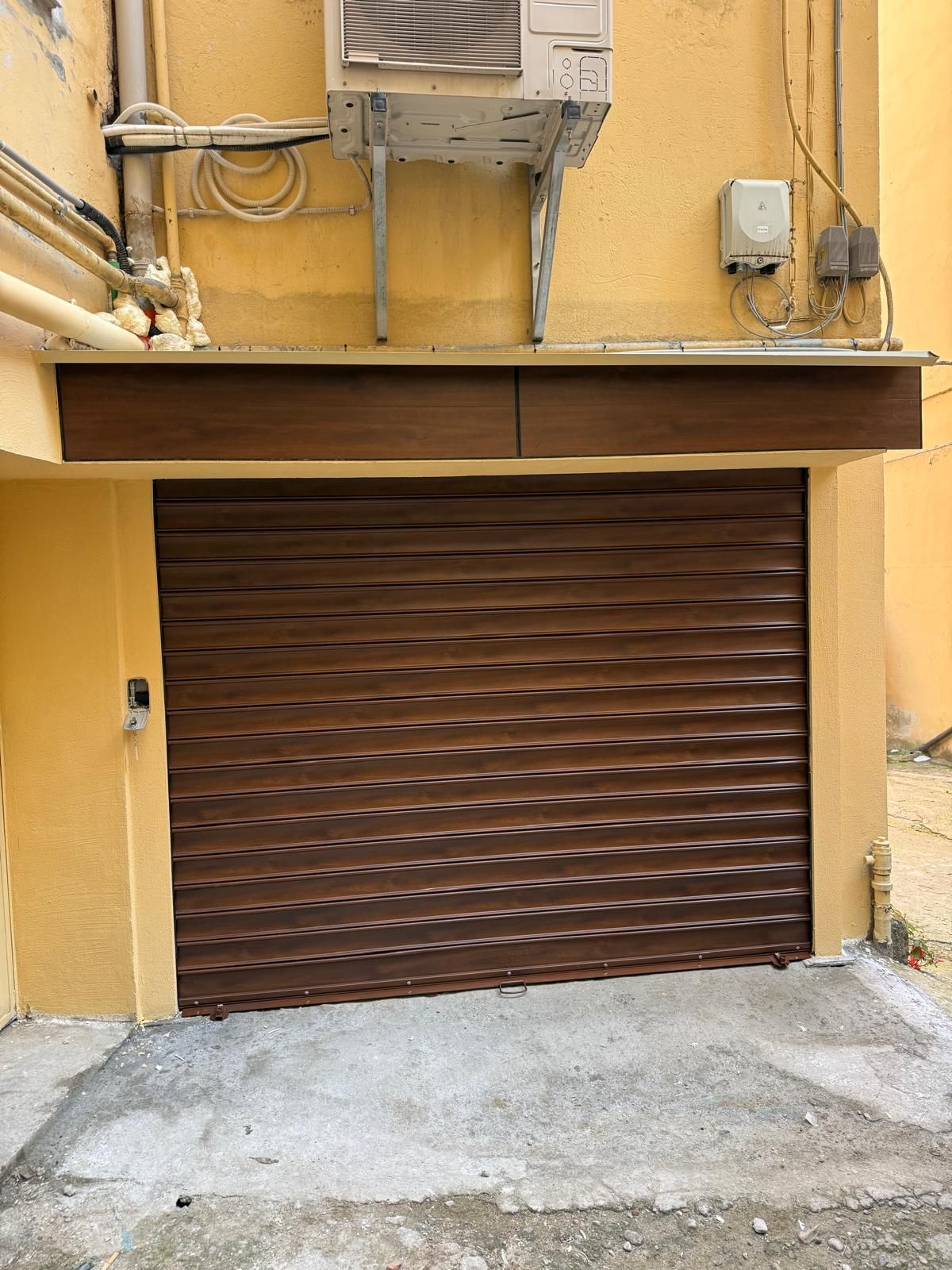 Porta da garage in lamiera ondulata marrone in un edificio giallo.