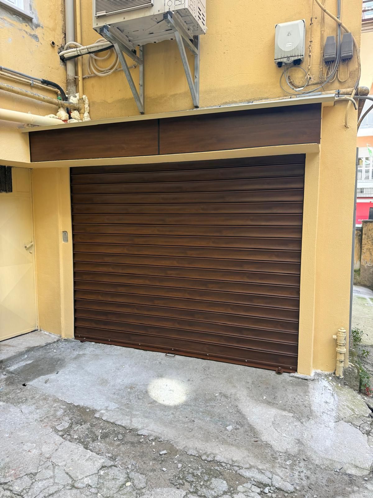 Porta di sicurezza in metallo ondulato marrone su un edificio giallo.
