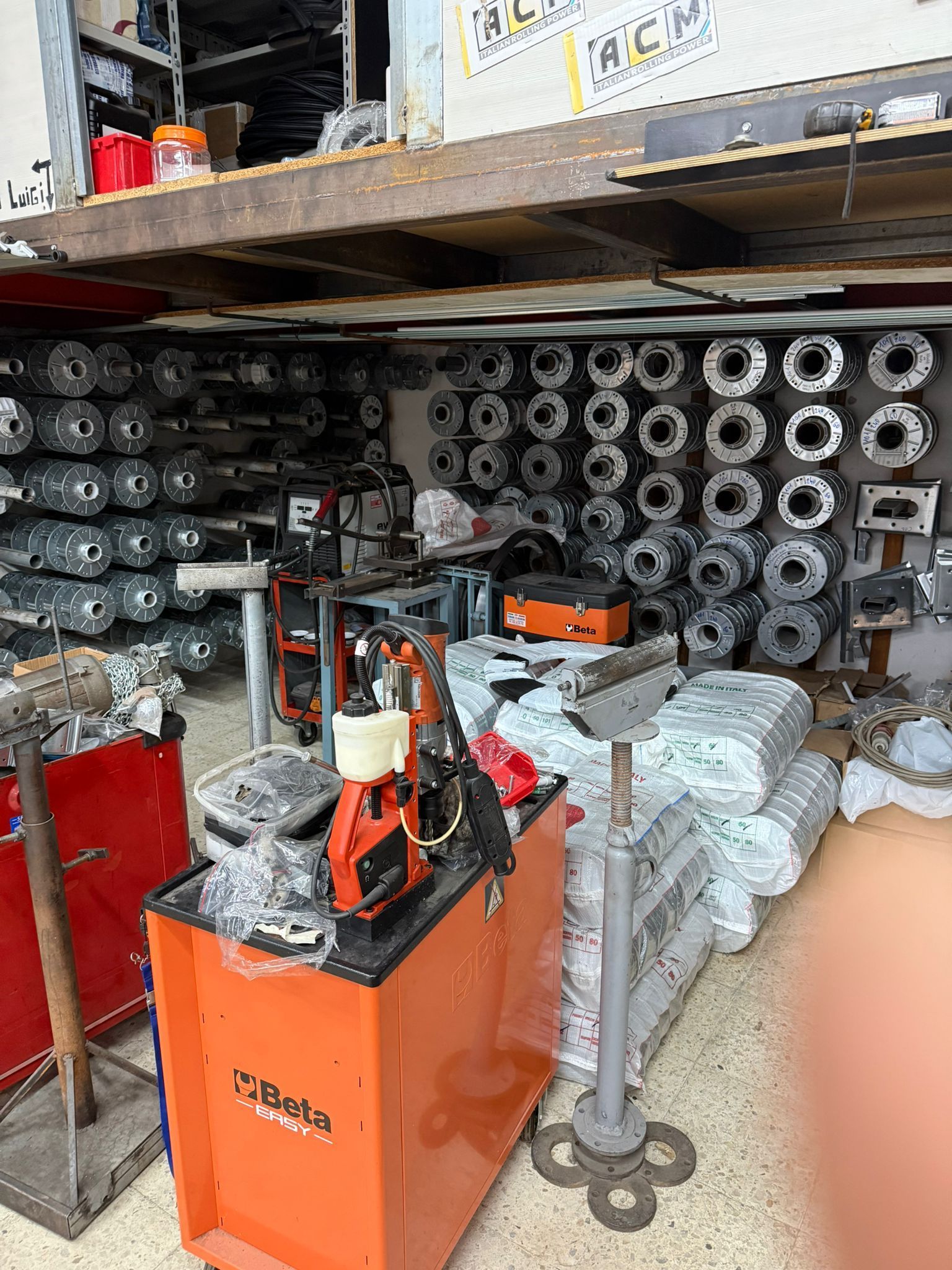 All'interno di un negozio disordinato, i pezzi del motore sono conservati su scaffali e pile, con alcuni utensili in vista.