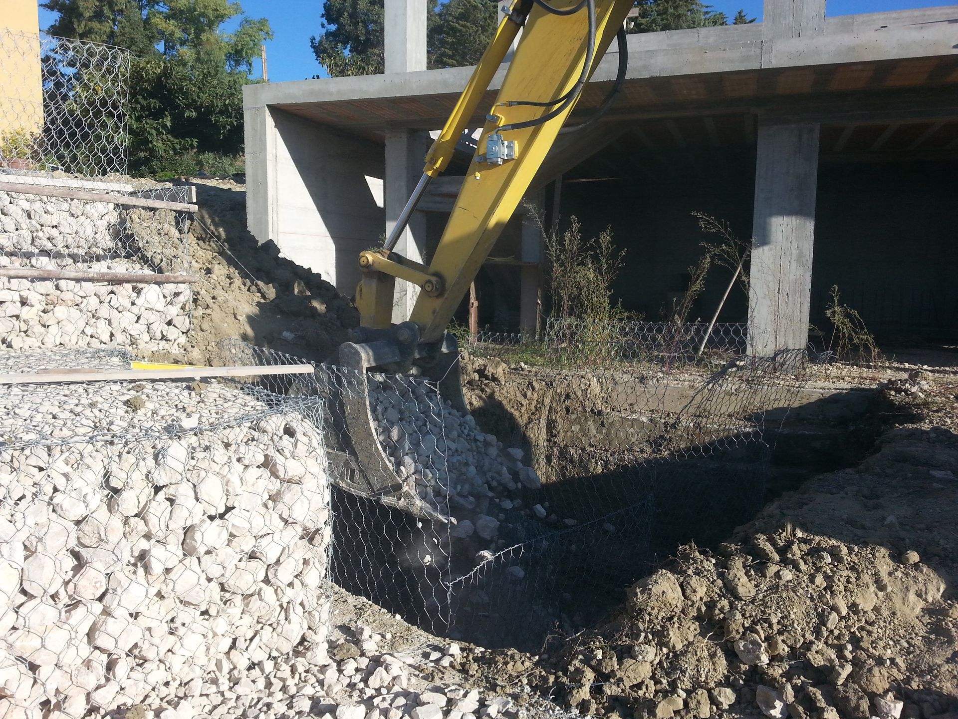 Un escavatore giallo sta scavando una buca nel terreno