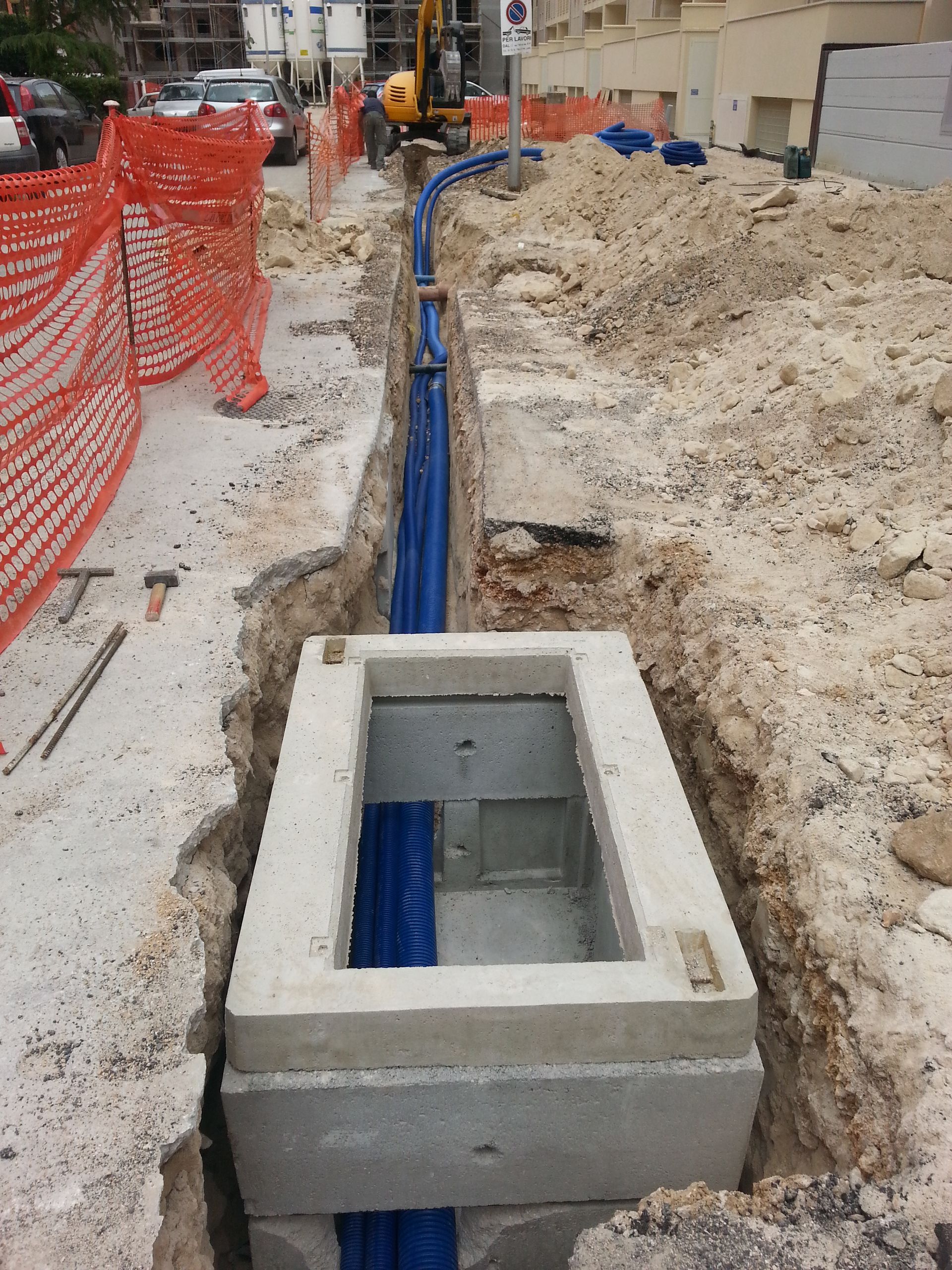 Un buco nel terreno da cui escono tubi blu