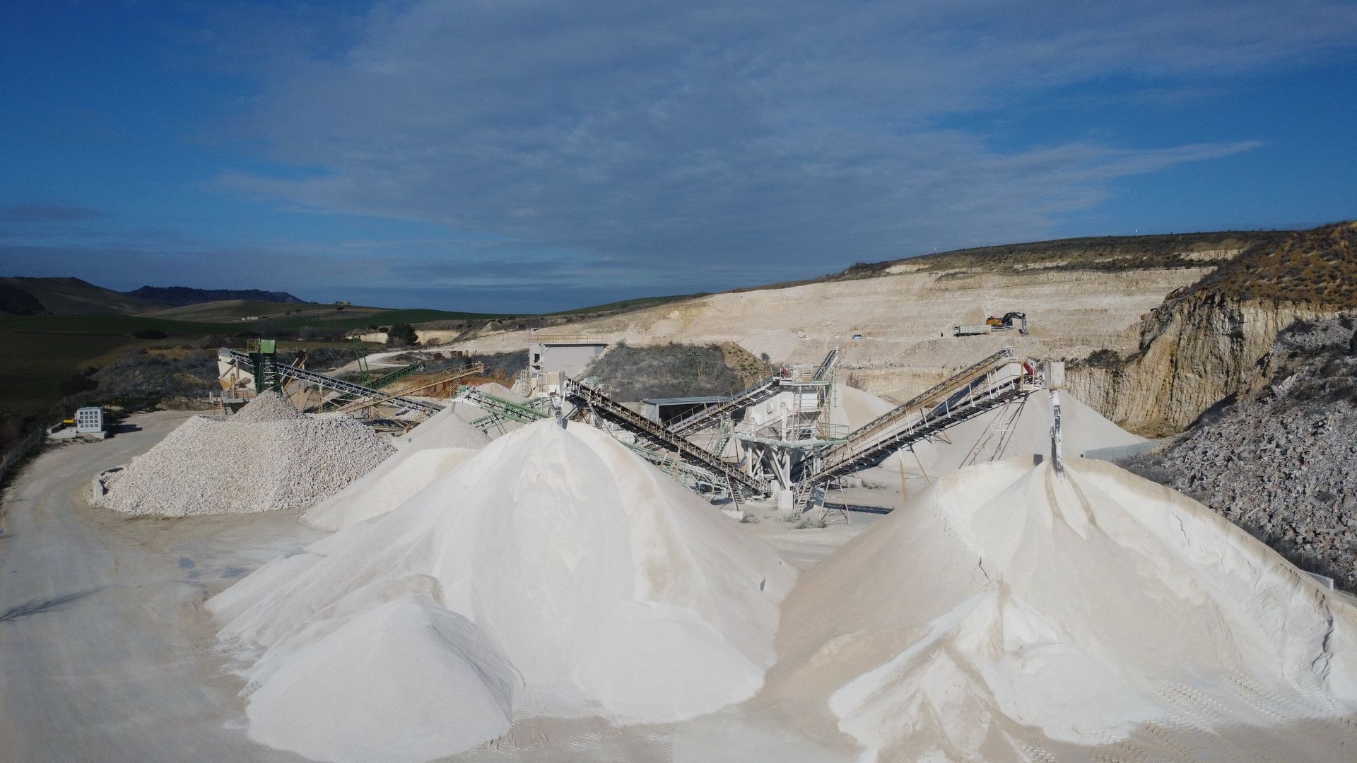 Un grande mucchio di sabbia bianca è adagiato in cima a una strada sterrata.