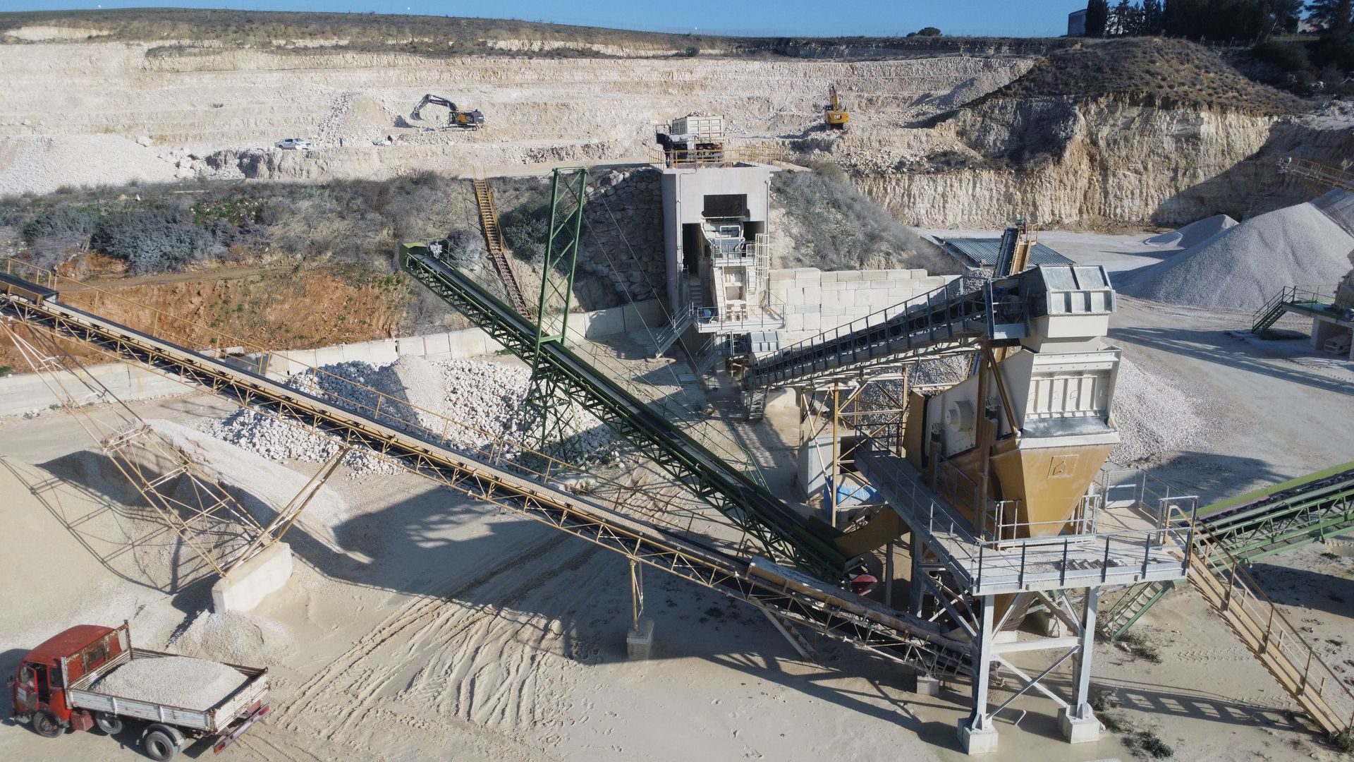 Una vista aerea di una cava con nastri trasportatori e un camion in primo piano.