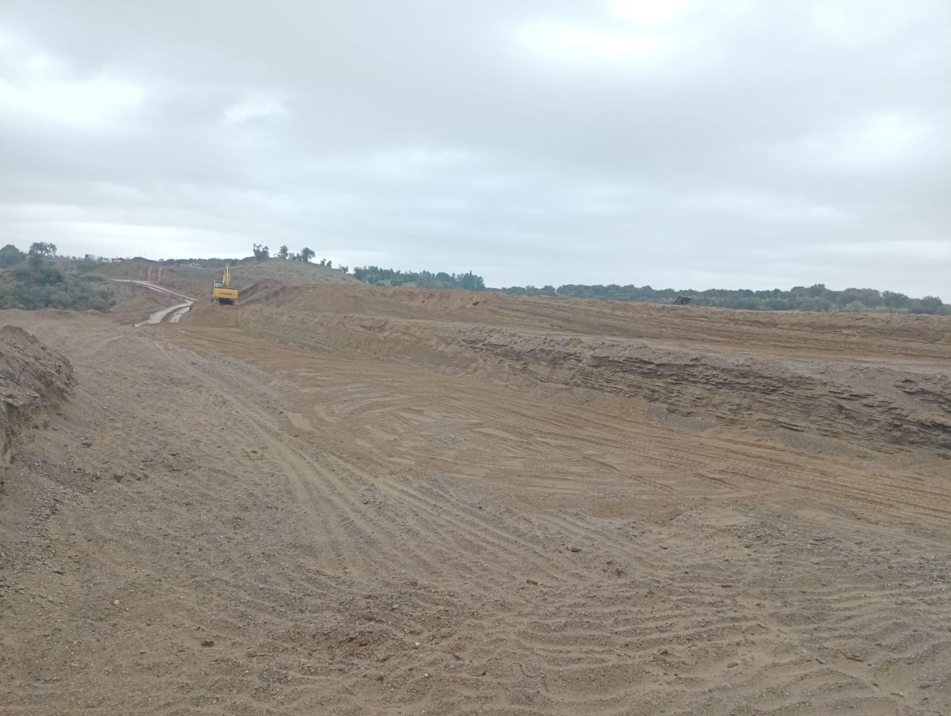 Una strada sterrata che attraversa un campo sterrato con alberi sullo sfondo.