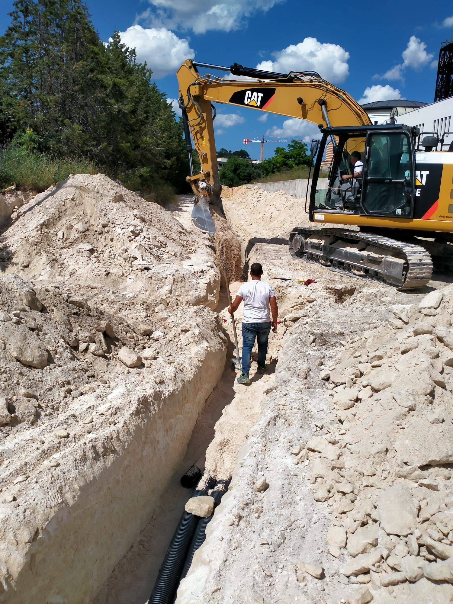Un uomo è in piedi nella polvere accanto a un grande escavatore.