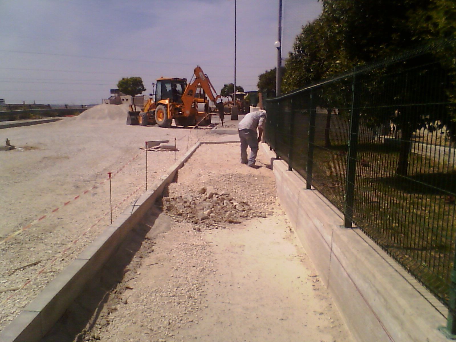 Un cantiere con una recinzione e un trattore sullo sfondo