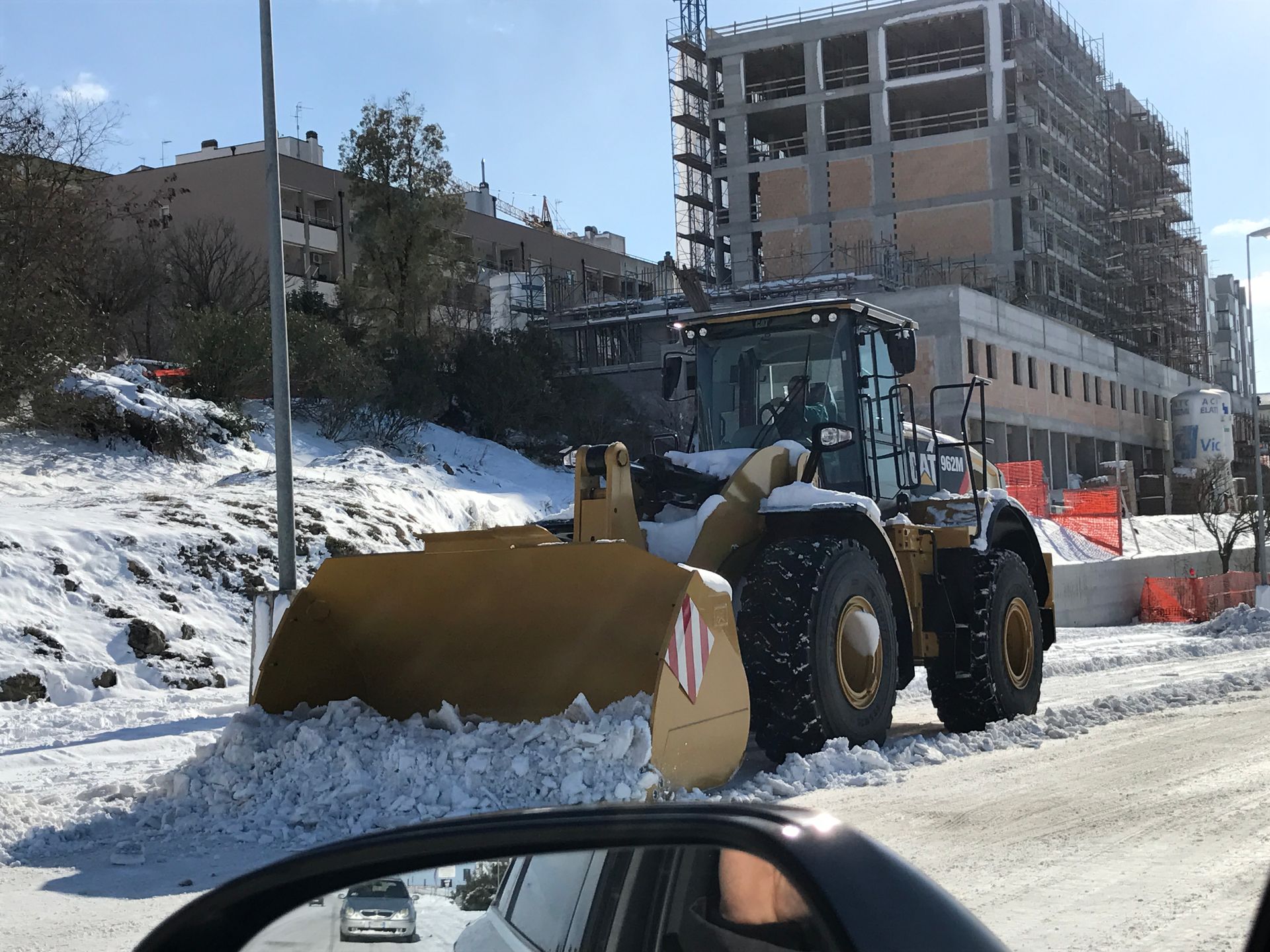 Una ruspa sta rimuovendo la neve ai lati della strada