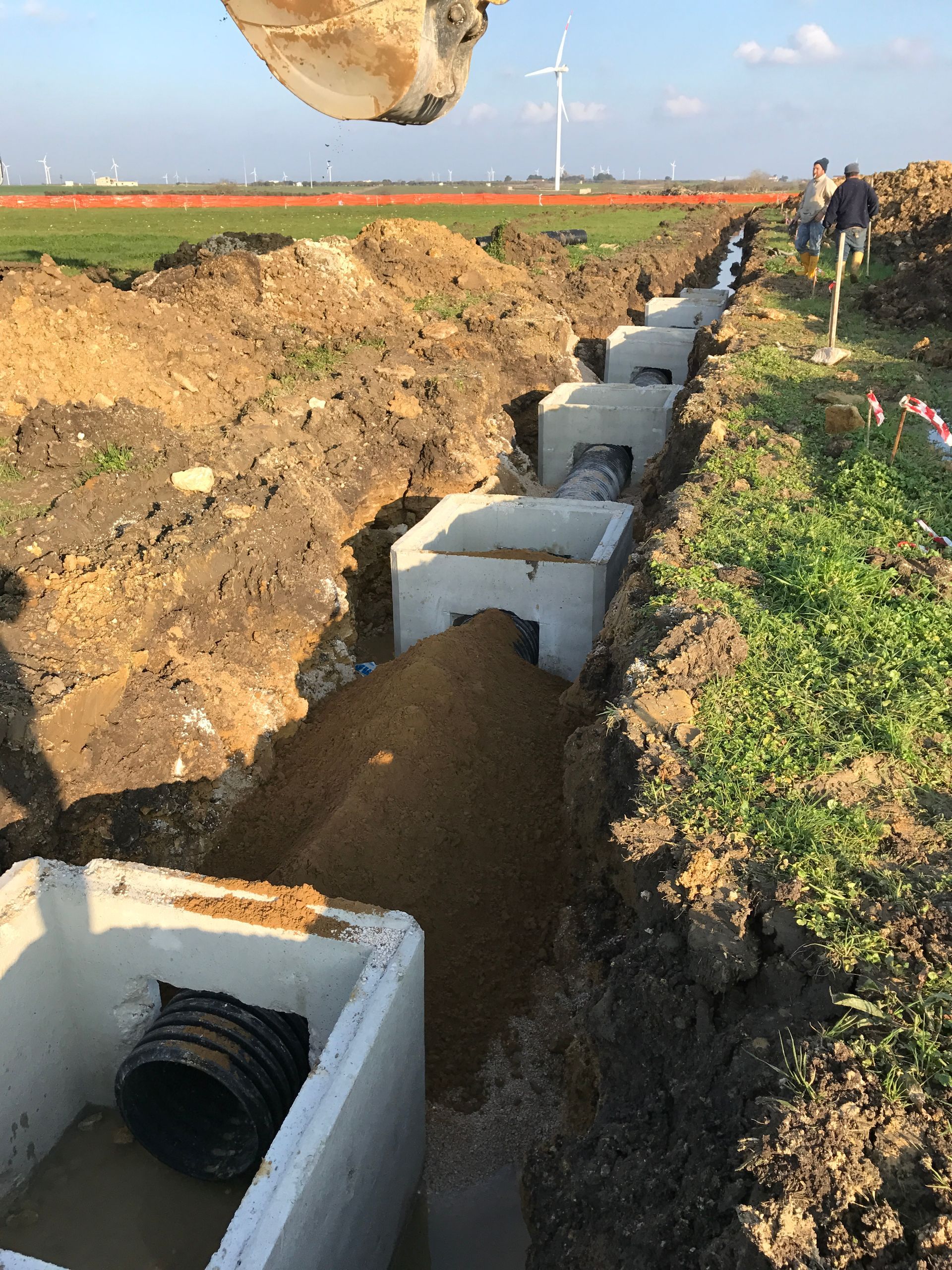 Un uomo sta scavando una trincea in un campo con una ruspa.