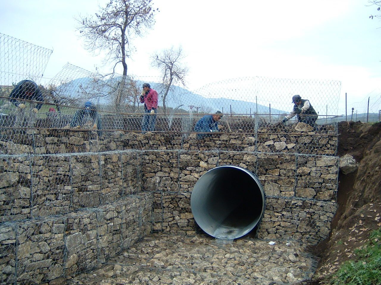 Un gruppo di persone sta lavorando su un muro di pietra accanto a un grande tubo.