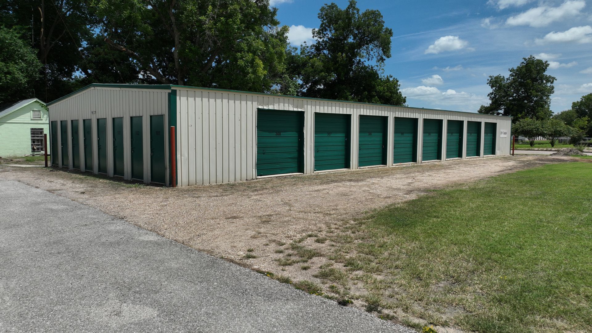 Ground-level view of drive-up storage units with green doors at Marlin EZ Storage in Marlin, TX.