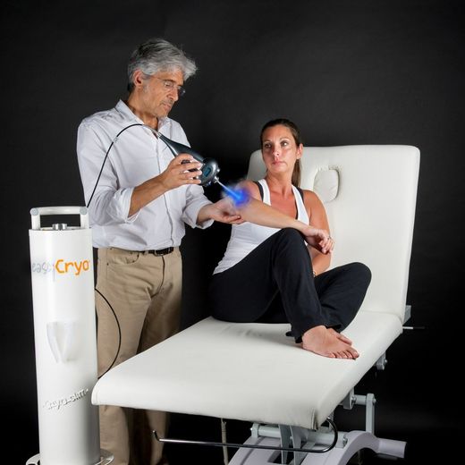 Practitioner using a cryotherapy device on a seated patient in a treatment room