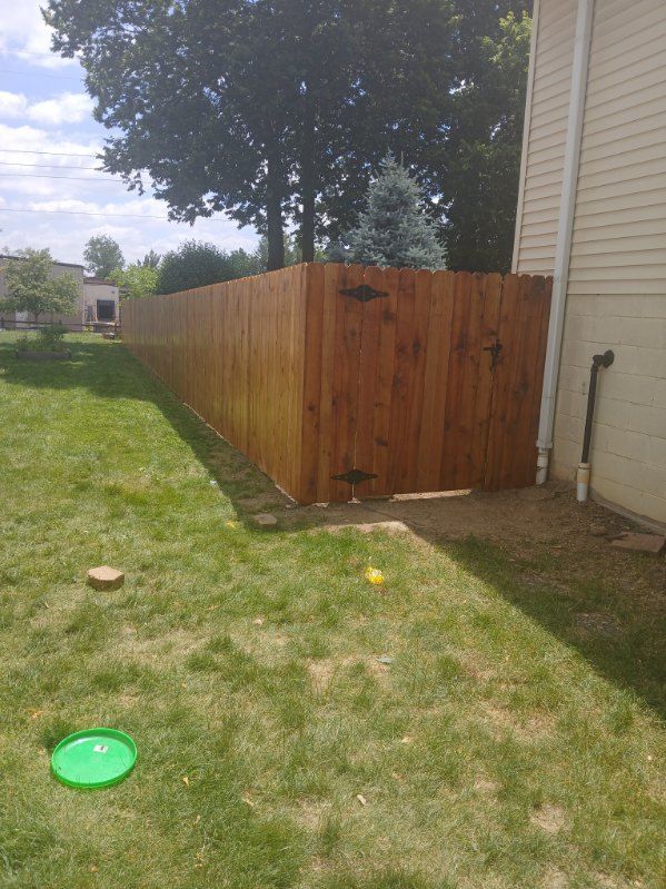 A wooden fence with a gate in the backyard of a house.