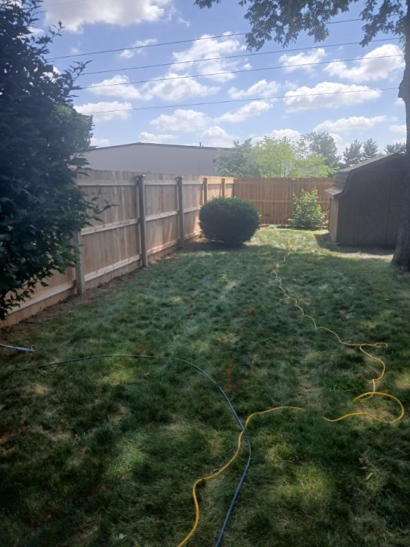 A backyard with a wooden fence and a lot of grass.