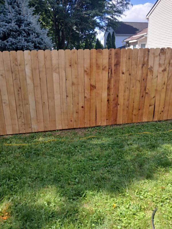 A wooden fence is sitting in the middle of a lush green yard.