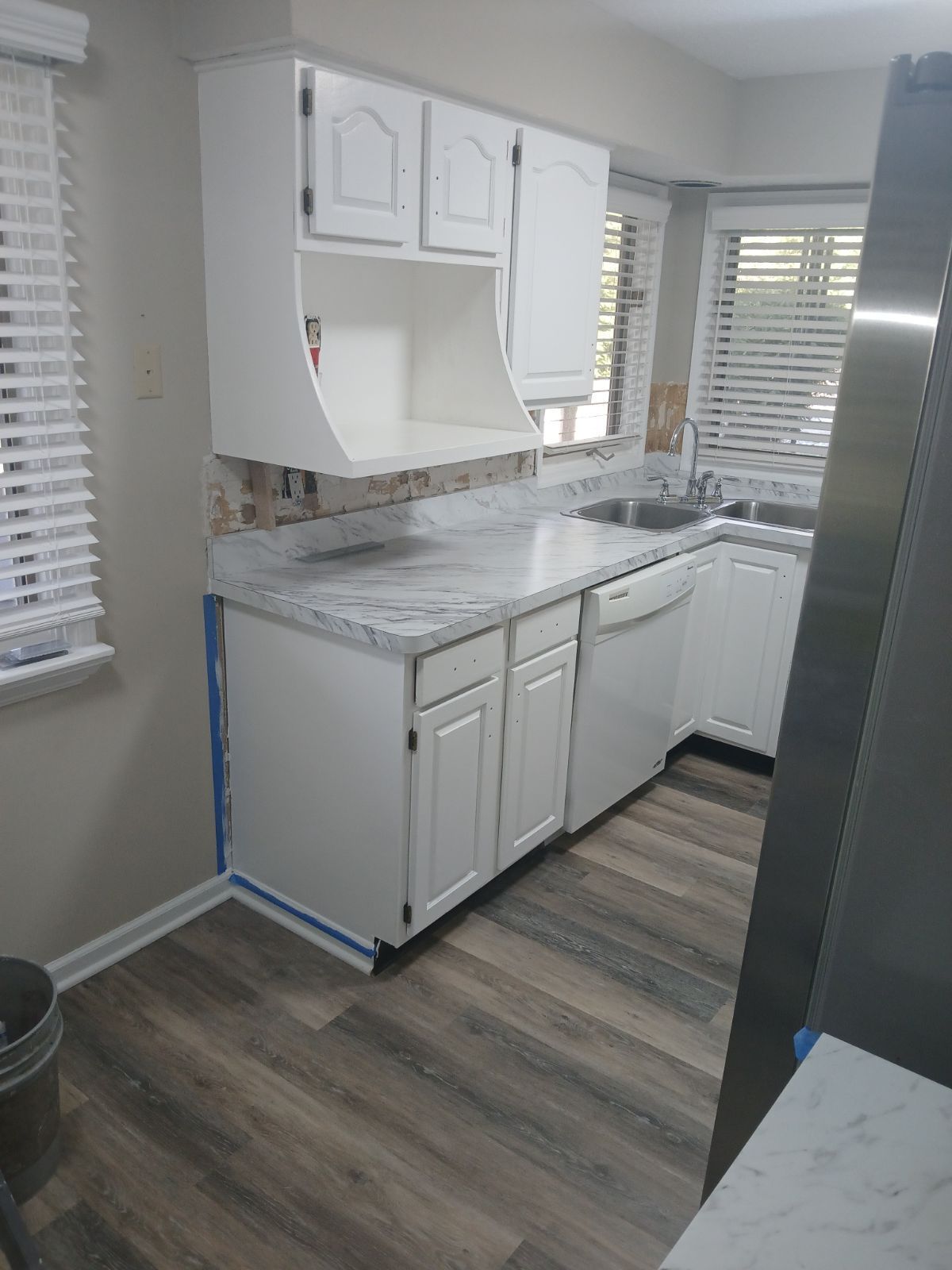A kitchen with white cabinets , granite counter tops , a sink , and a refrigerator.