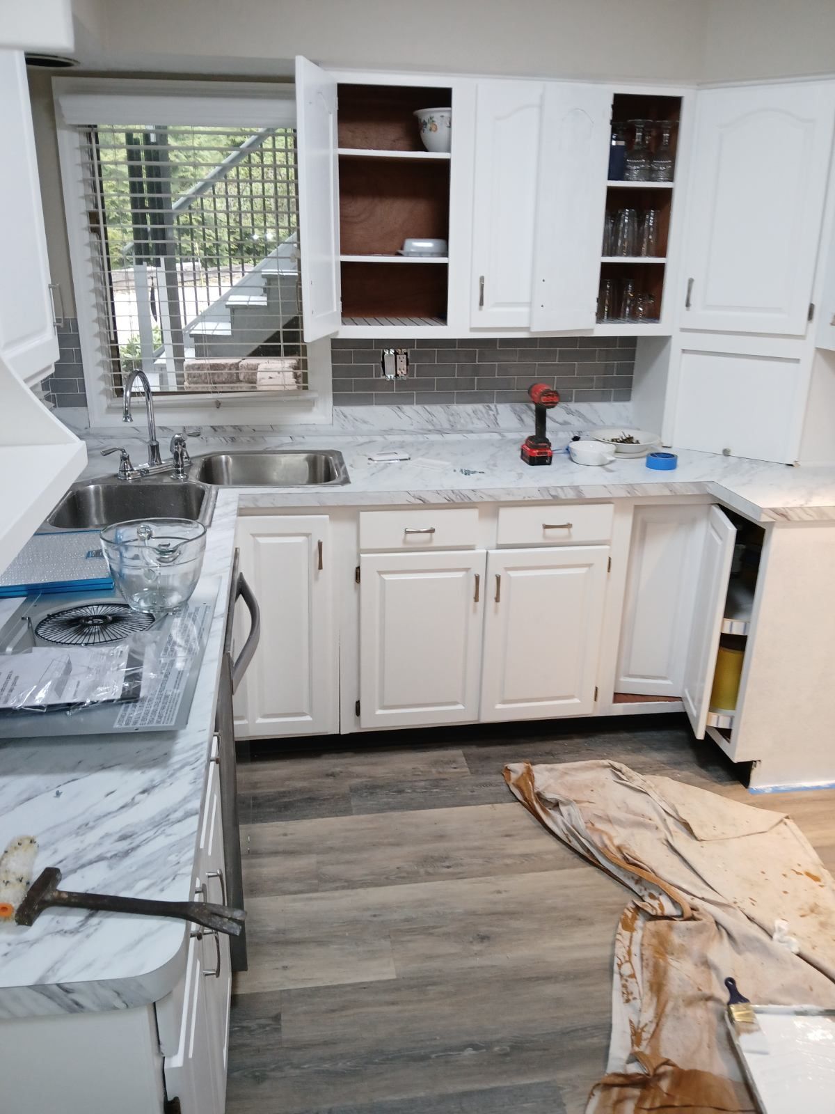 A kitchen with white cabinets , a sink , and a stove.