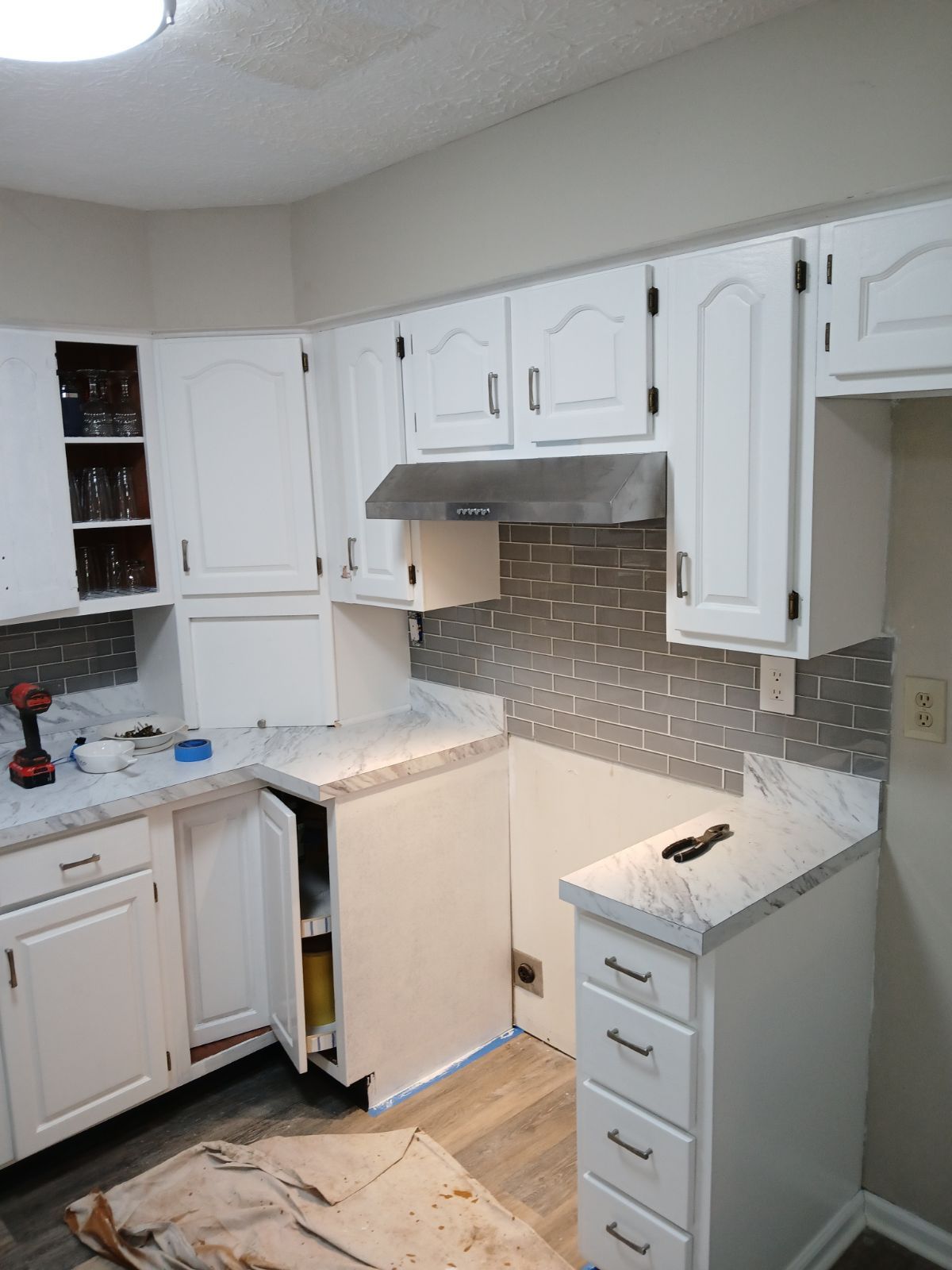 A kitchen with white cabinets and a stove top oven.