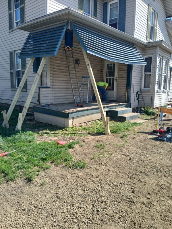 A man is working on the porch of a house.