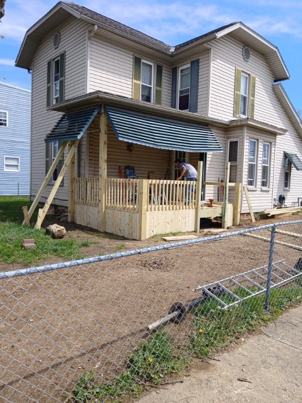 A man is working on a porch in front of a house.