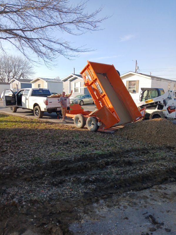 A man is standing next to a dumpster that is being pulled by a truck.