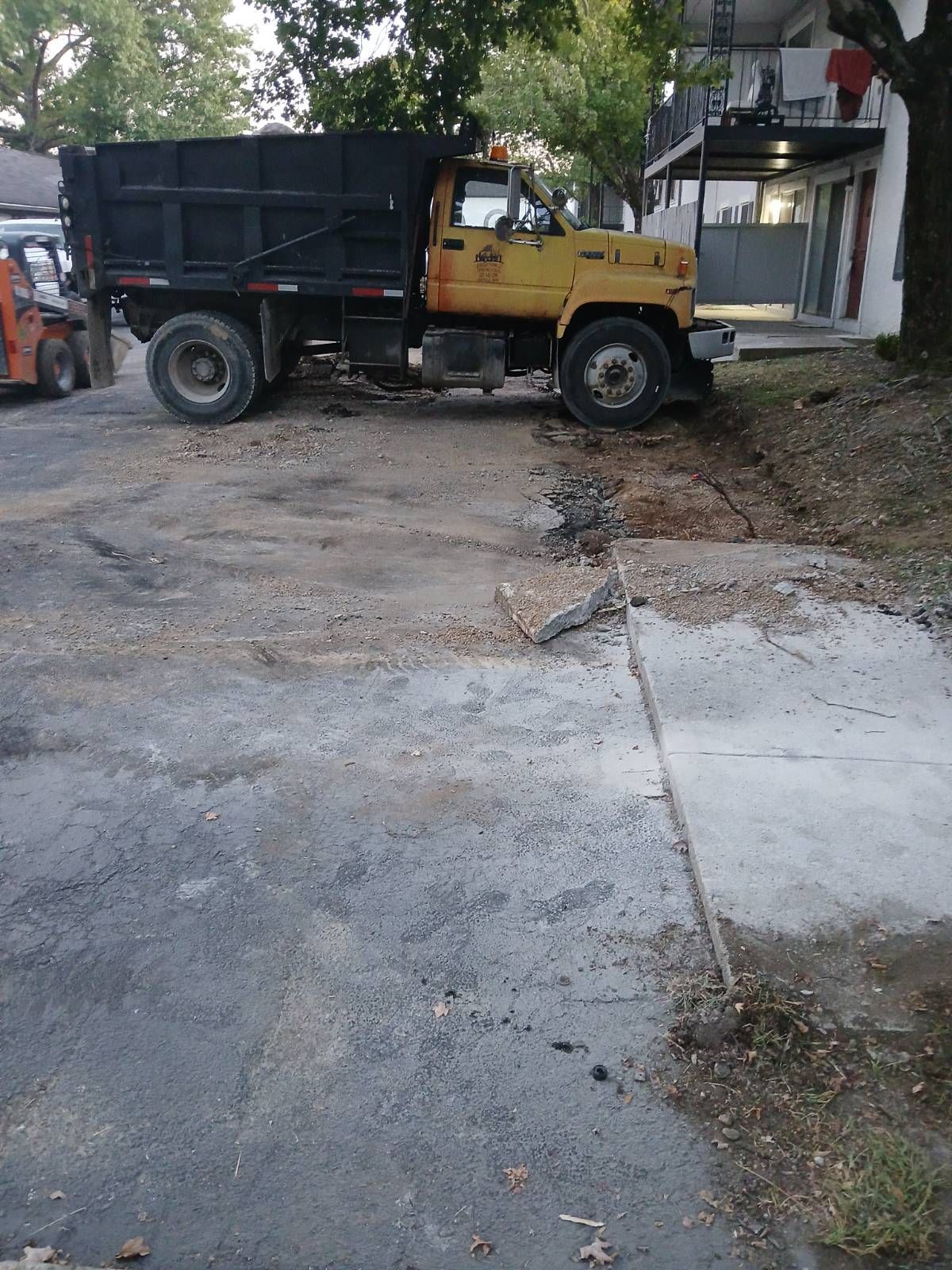 A yellow dump truck is parked on the side of the road.