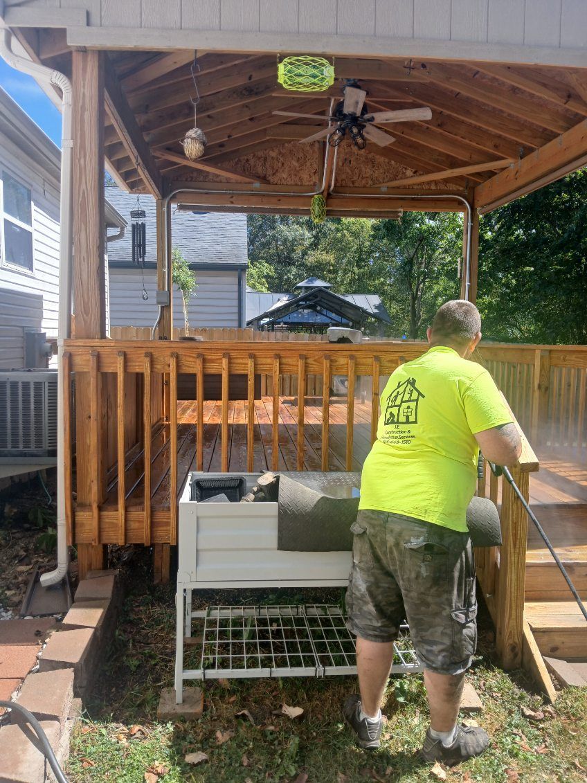 A man is cleaning a deck with a pressure washer.