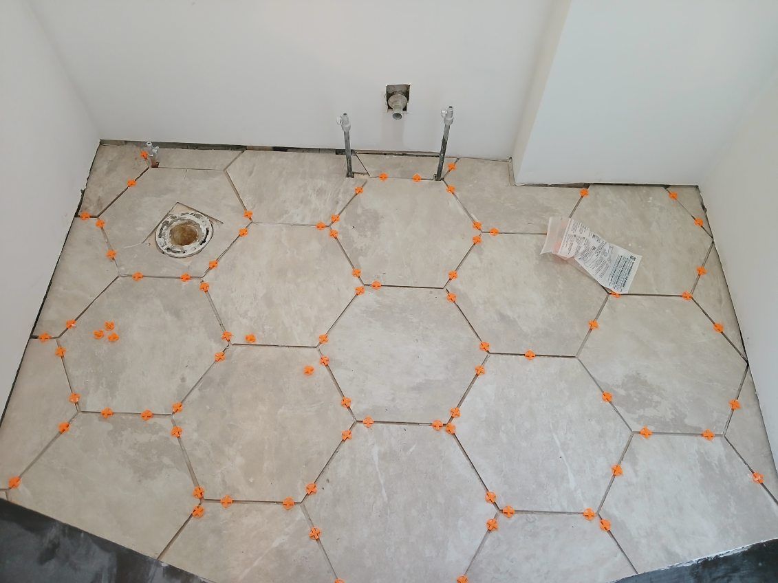 A bathroom floor with hexagonal tiles being installed.