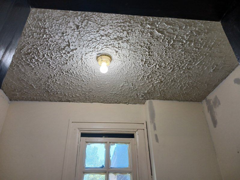 A light bulb is hanging from the ceiling of a room next to a window.