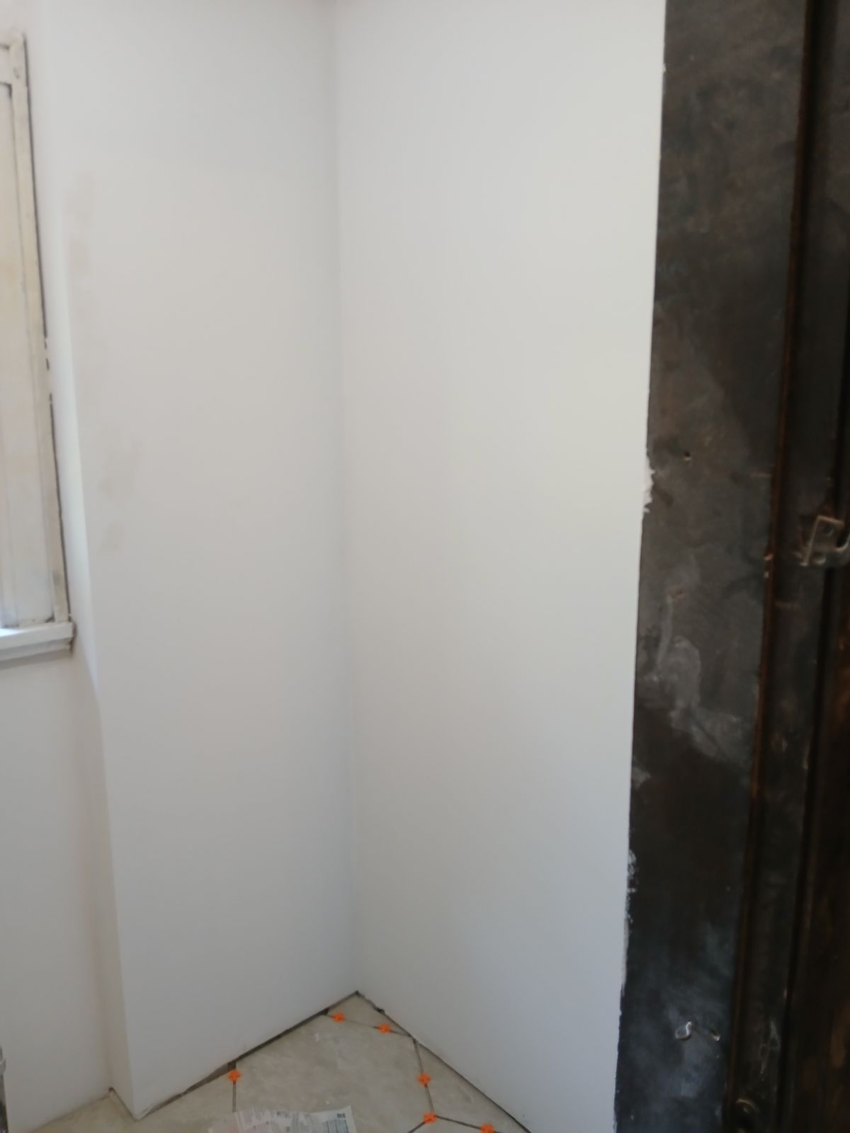 A corner of a room with white walls and a window.