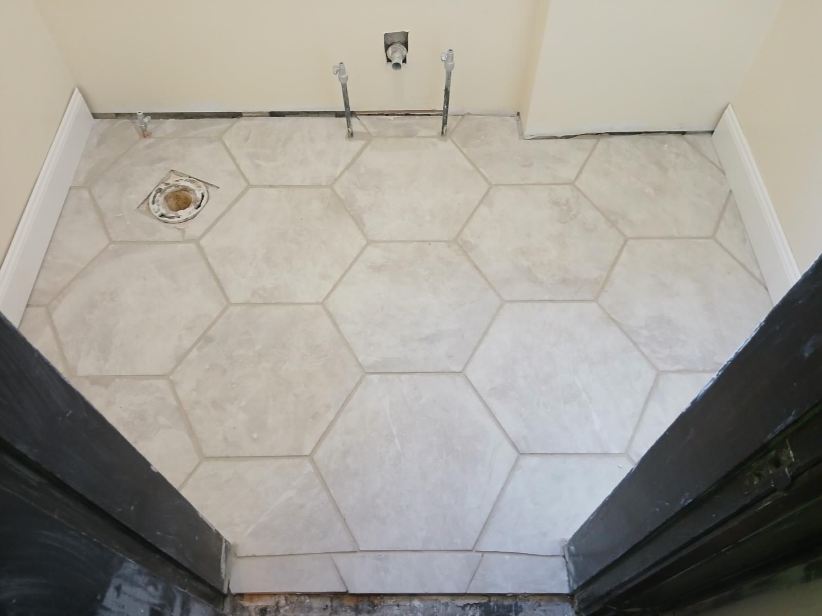 A bathroom with hexagonal tiles and a black door