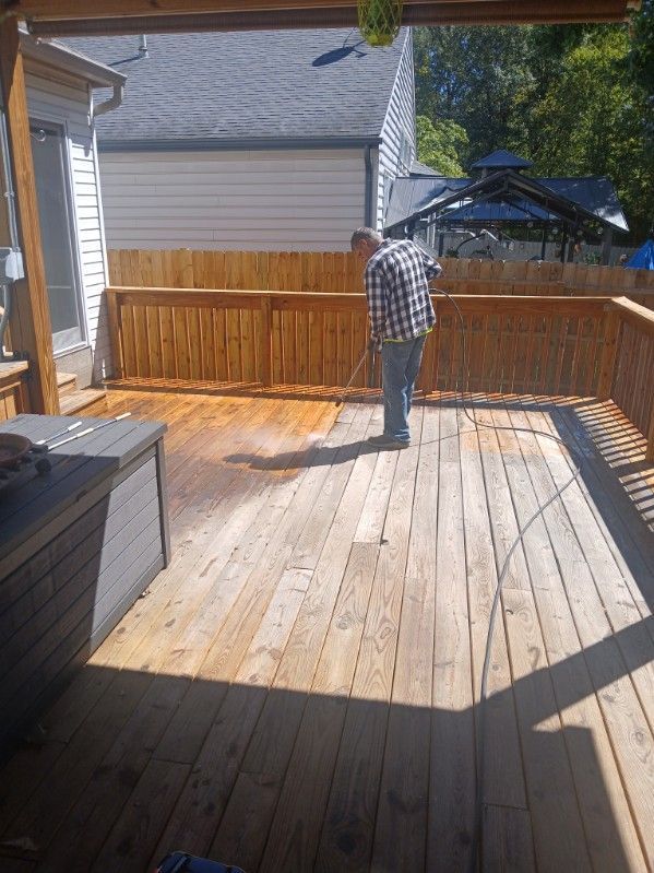 A man is cleaning a wooden deck with a broom.