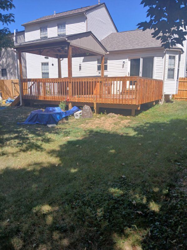 A large wooden deck is in the backyard of a house.