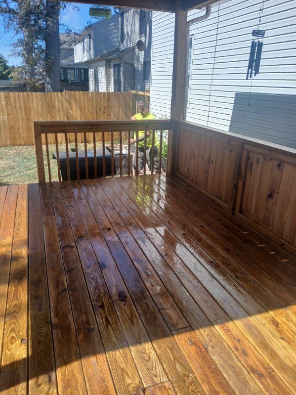 A wooden deck with a fence and a house in the background.