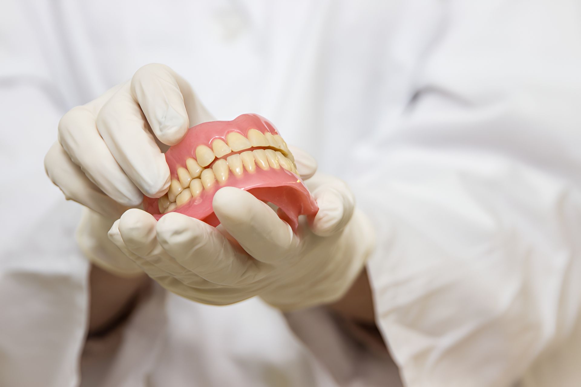 A Dentist is Holding a Model of Teeth in His Hands — Graham Johnson Dental Surgery In Jesmond, NSW