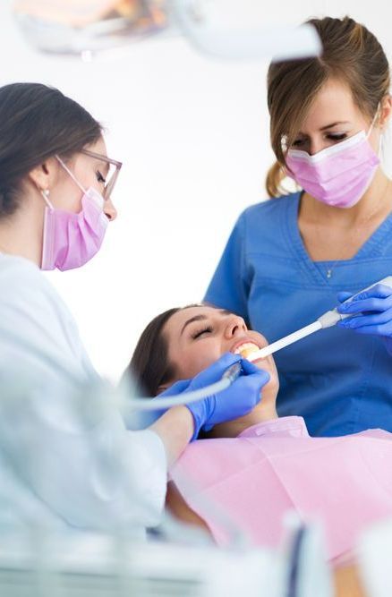 A Woman is Getting Her Teeth Examined by Two Female Dentists — Graham Johnson Dental Surgery In Beresfield, NSW